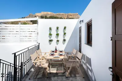 a balcony with a table and chairs on a white wall at Lindos Heart Apartments in Líndos