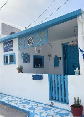 a white building with a blue door and a porch at Peters Studio in Archangelos