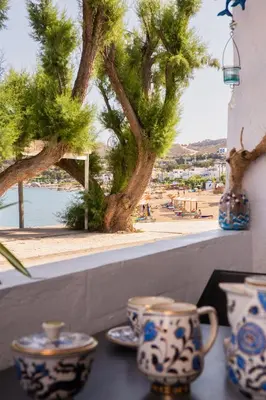 a table with blue and white cups and a view of the beach at Peters Studio in Archangelos