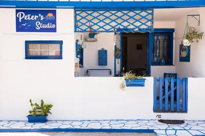 a white building with a blue gate and a door at Peters Studio in Archangelos
