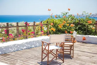 two chairs sitting on a deck with the ocean in the background at Villa Helios in Kalathos