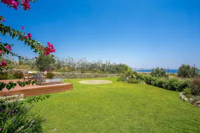 a large grassy yard with a bench and flowers at Villa Helios in Kalathos