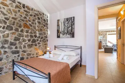 a bedroom with a bed and a stone wall at Villa Helios in Kalathos