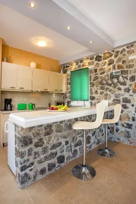 a kitchen with a stone wall with a counter and chairs at Villa Helios in Kalathos