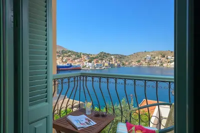 a balcony with a table and a view of the water at Astradeni House by Blue Wave in Symi