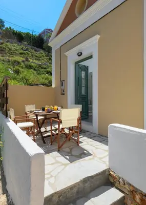 a patio with a table and chairs in front of a house at Astradeni House by Blue Wave in Symi