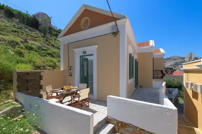 a small house with a patio with a table at Astradeni House by Blue Wave in Symi