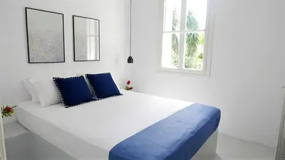 a white bedroom with a large bed with blue pillows at 30villa Rd in Rhodes Town