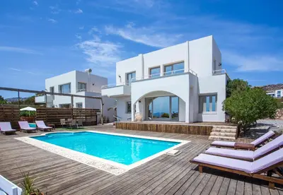 a villa with a swimming pool in front of a house at Spilia Bay Villas in Pefki Rhodes