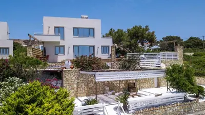 a large white house with a stone wall at Spilia Bay Villas in Pefki Rhodes