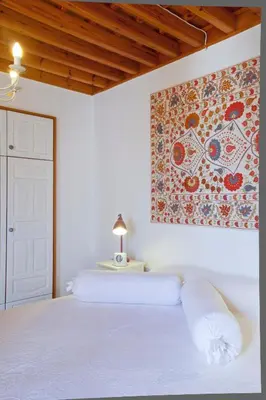 a bedroom with a white bed with a painting on the wall at Villa Lindos in Líndos