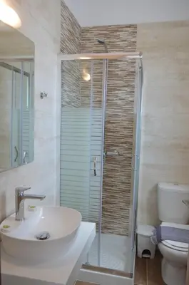 a bathroom with a shower and a sink and a toilet at Gennadi Gardens exclusive apartments in Gennadi