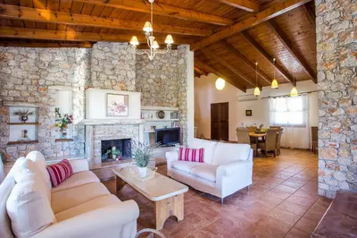 a living room with white furniture and a stone wall at Sunny Countryside Villa - With private pool in Faliraki