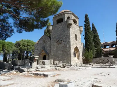 an old stone church with a tower in a park at Vivian Studios in Ialyssos