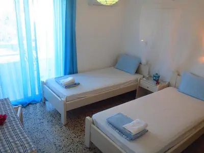 two beds in a small room with blue curtains at Vivian Studios in Ialyssos