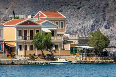 a small boat in the water in front of houses at Villa Galanis in Symi