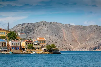 a town on the water with mountains in the background at Villa Galanis in Symi