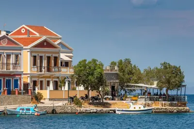 a house on the water with boats in the water at Villa Galanis in Symi