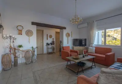 a living room with orange couches and a tv at Ktima Argyrou Stegna in Archangelos