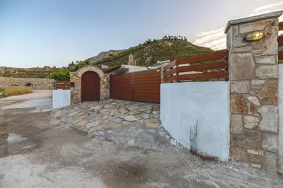 a house with a wooden gate and a fence at Ktima Argyrou Stegna in Archangelos