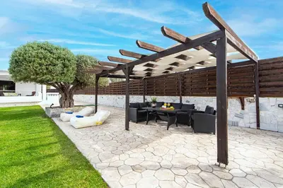 an outdoor patio with a wooden pergola at Marble Pool Villa in Pastida