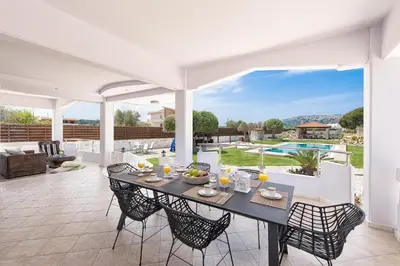 a dining room with a table and chairs on a patio at Marble Pool Villa in Pastida