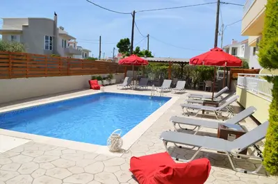 a swimming pool with chairs and red umbrellas at Kremasti Memories in Kremasti