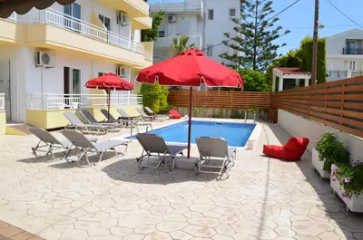 a patio with chairs and umbrellas next to a pool at Kremasti Memories in Kremasti
