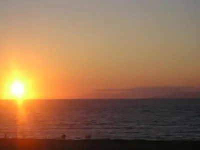 a sunset over the ocean with people on the beach at Nirvana Beach Hotel in Theologos