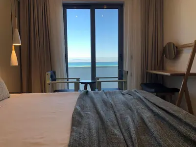 a bedroom with a bed and a view of the ocean at Nirvana Beach Hotel in Theologos