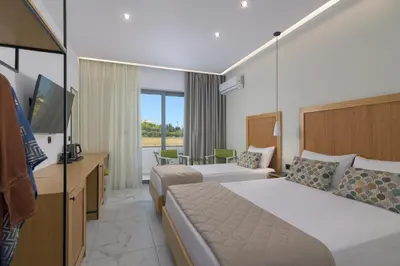 a hotel room with two beds and a television at Nirvana Beach Hotel in Theologos