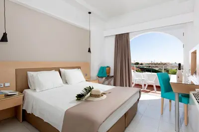 a bedroom with a bed and a desk and a balcony at Kolymbia Sun in Kolimbia