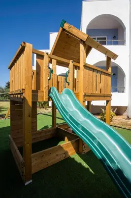 a wooden playset with a slide on a lawn at Kolymbia Sun in Kolimbia