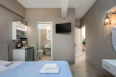 a bedroom with a blue bed and a bathroom at Maravelia's Rooms in Symi