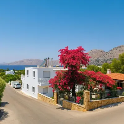 a white house with a tree with red flowers at George Beach Studios in Pefki Rhodes