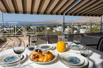 a table with plates of food and glasses of wine at George Beach Studios in Pefki Rhodes