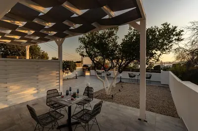 a patio with a table and chairs under a pergola at George Beach Studios in Pefki Rhodes