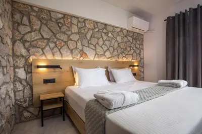 a bedroom with two beds and a stone wall at Jimmy’s Garden in Faliraki