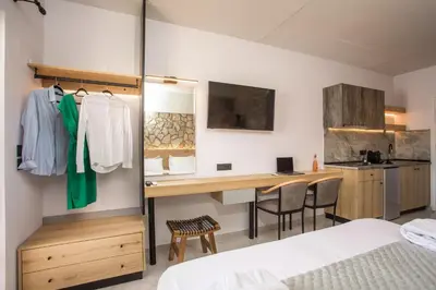 a bedroom with a bed and a desk and a kitchen at Jimmy’s Garden in Faliraki