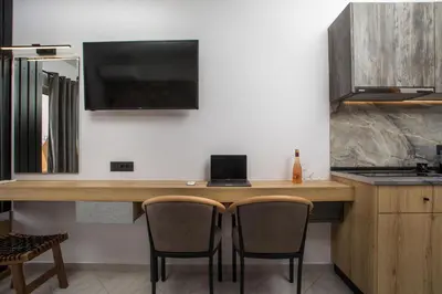 a kitchen with a table with two chairs and a television at Jimmy’s Garden in Faliraki