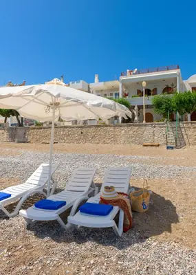 two lounge chairs and an umbrella on a beach at Haraki Sea View Luxury House in Rhodes Town