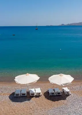 two white umbrellas and chairs on a beach at Haraki Sea View Luxury House in Rhodes Town