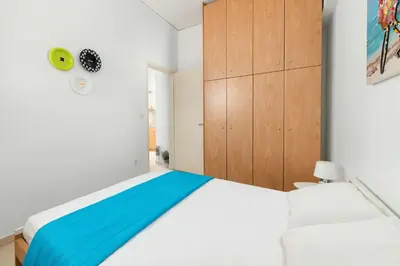 a bedroom with a white bed and wooden cabinets at Maximos Sea & The City in Rhodes Town