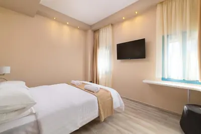 a hotel room with a bed and a flat screen tv at Royal Villa Pedi in Symi