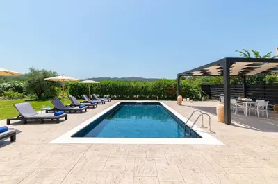 a swimming pool with lounge chairs and an umbrella at Villa Sophia in Soroni