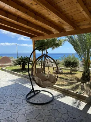 a swing on a patio with the ocean in the background at Villa Rose in Archangelos
