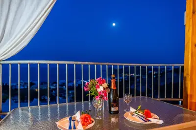 a table with a bottle of wine and flowers on a balcony at Villa Rose in Archangelos