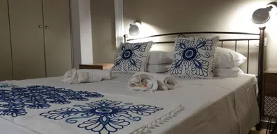 a bed with blue and white sheets and pillows at Ria's Deluxe Apartments in Faliraki