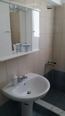 a bathroom with a white sink and a mirror at Ria's Deluxe Apartments in Faliraki