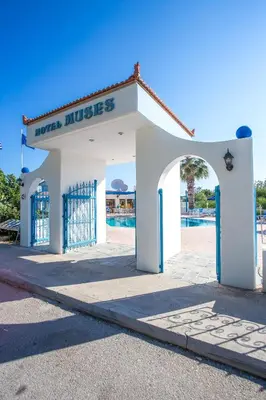a white building with an archway in front of a pool at Muses Hotel in Faliraki